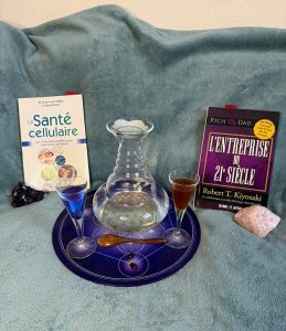 Illustration de la santé cellulaire au naturel : carafe d'eau Aladin, compléments alimentaires, livres de référence et cristaux énergétiques sur fond apaisant
